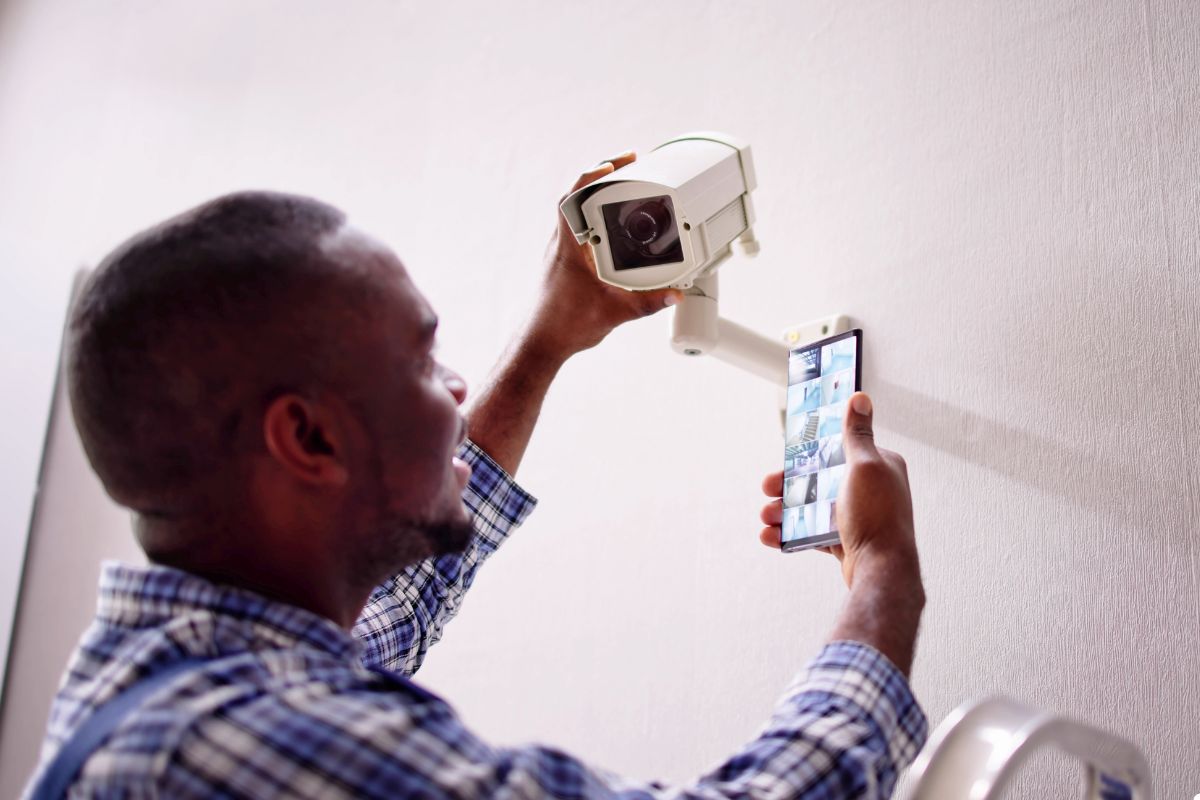 A man is using a cell phone to take a picture with a camera, showcasing a blend of technology and photography.